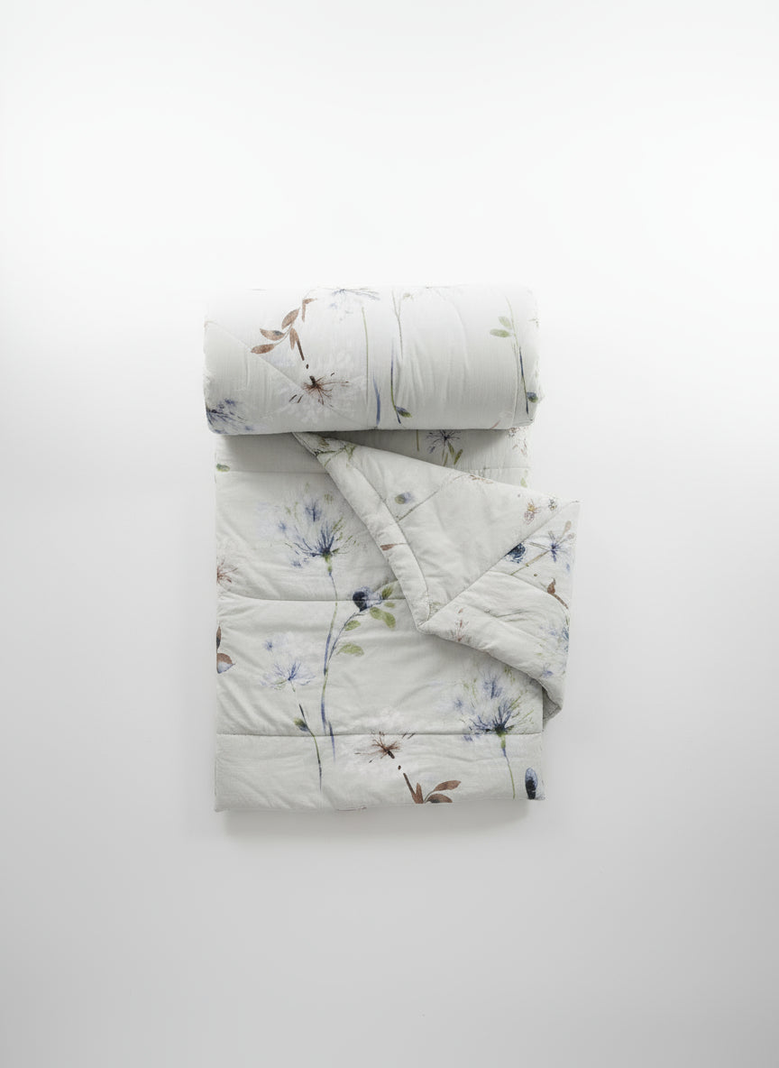 Floral-patterned quilt and pillow on a plain background