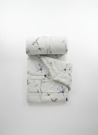 Floral-patterned quilt and pillow on a plain background