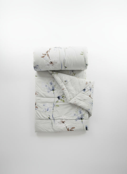 Floral-patterned quilt and pillow on a plain background