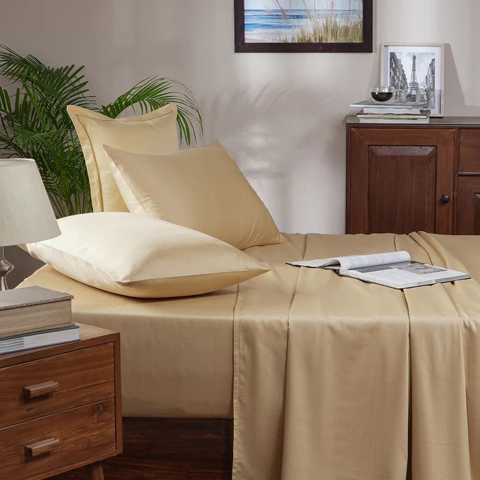 Beige bed sheets and pillows on a neatly made bed in a bedroom setting.